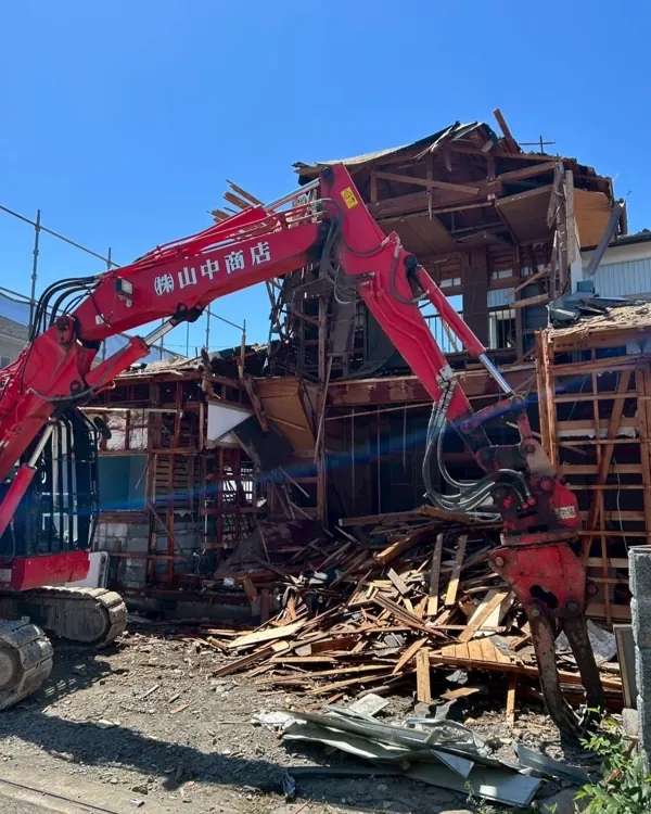 山中商店の赤い重機が木造住宅を解体している現場